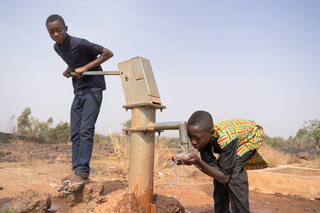 Enfants tirant de l'eau à la pompe